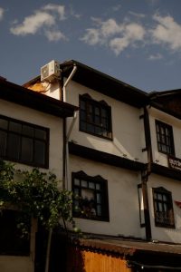 Historic architecture building with vintage windows and AC unit under bright blue sky with clouds.