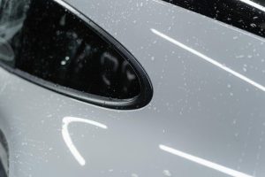 A detailed view of a white car with water droplets after a wash, showcasing its shine.